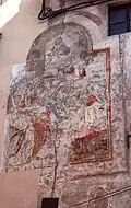 Affresco di Madonna fra Santi sulla facciata di una casa in Via Cesare Battisti